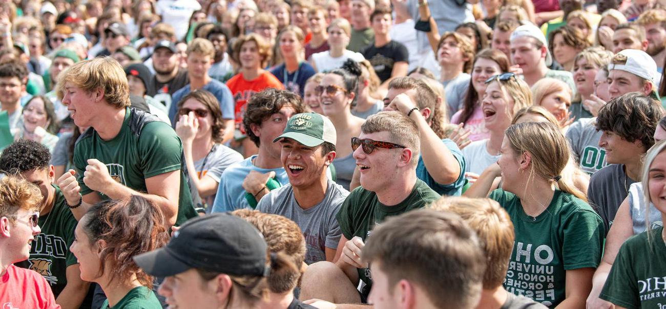 A group of newbb电子平台 students laugh 和 smile together after sitting in the st和s of a stadium