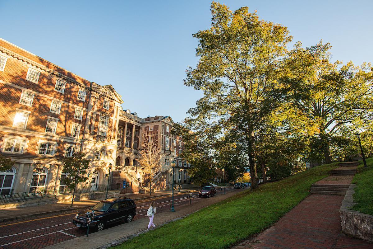 A student walks on the 雅典 Campus one fall morning, with brick buildings in the background